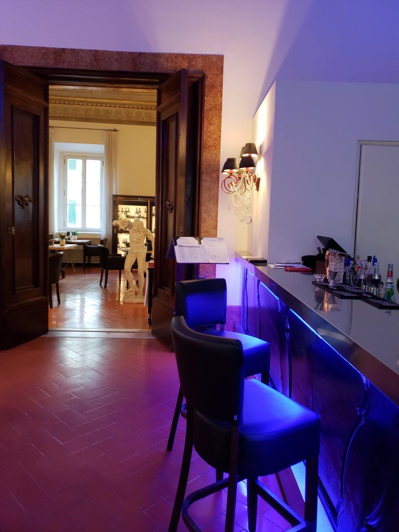 A room with a bar and chairs and purple lights