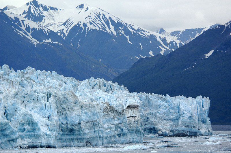 A large iceberg in the middle of a lake with mountains in the background