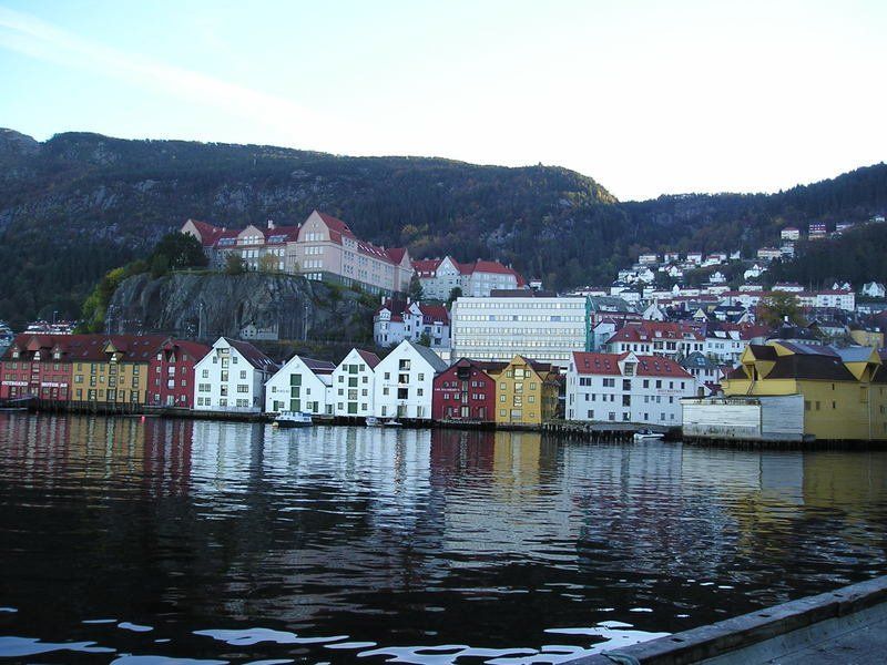 A row of buildings along a body of water with mountains in the background
