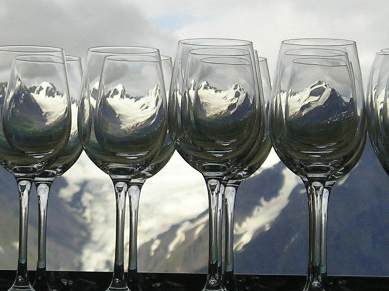 A row of wine glasses with mountains reflected in them