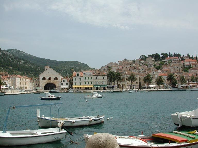 Several boats are docked in a harbor with buildings in the background