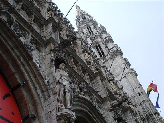 A statue of a man stands in front of a very tall building