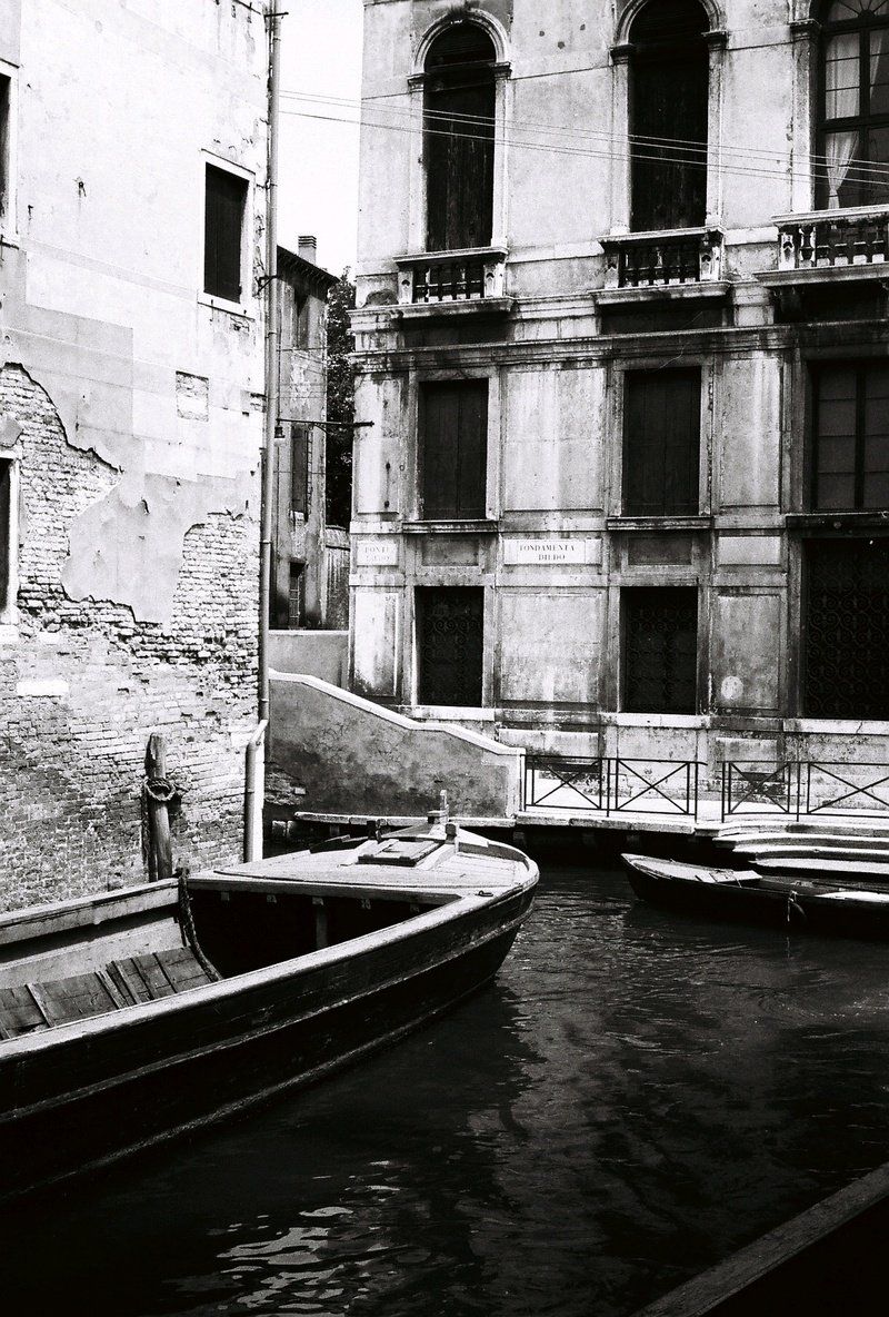 A black and white photo of a canal with boats in it