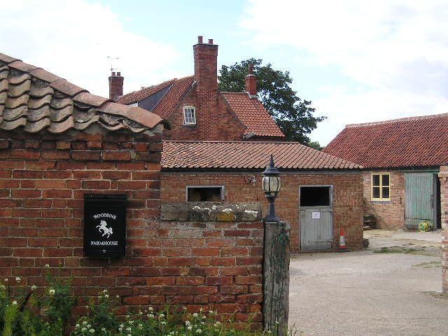 A black mailbox with a horse on it sits in front of a brick building