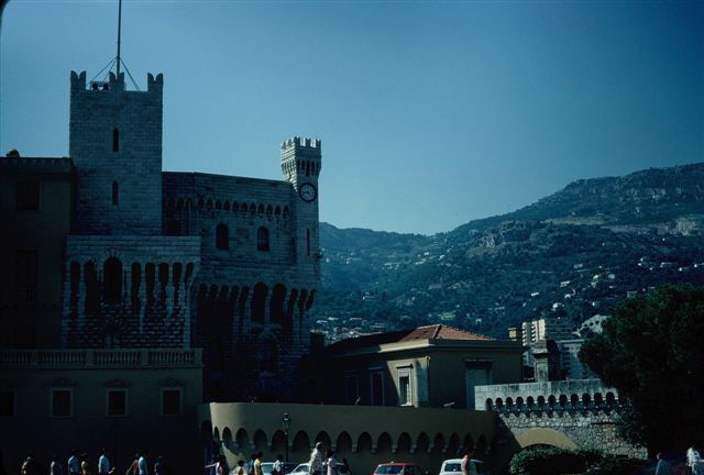 A large building with a clock tower on top of it is surrounded by mountains.