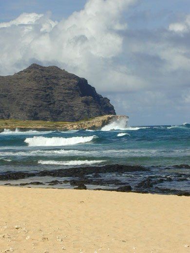 Waves crashing on a sandy beach with mountains in the background