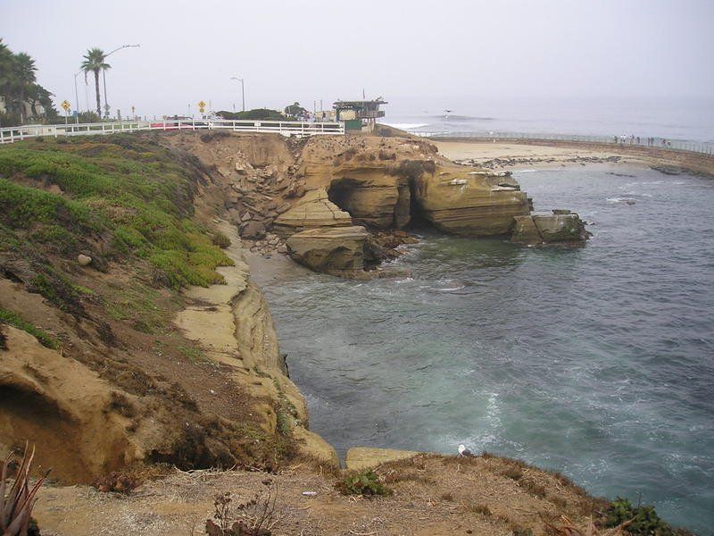 A cliff overlooking a body of water with a bridge in the background