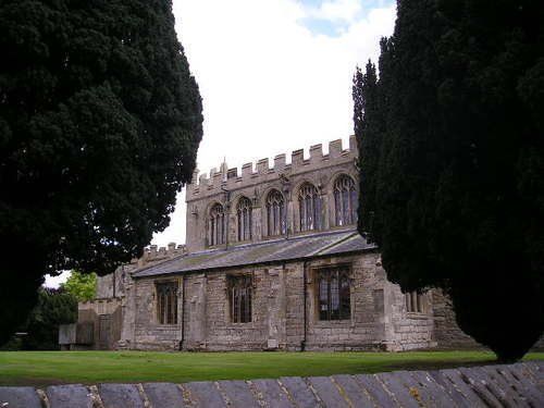 A large stone building with arched windows is surrounded by trees