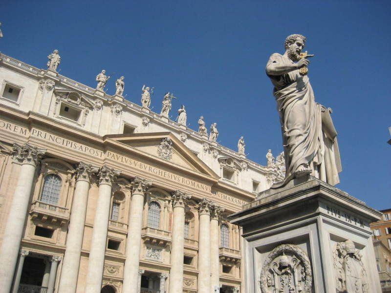 A statue in front of a building with columns and a blue sky