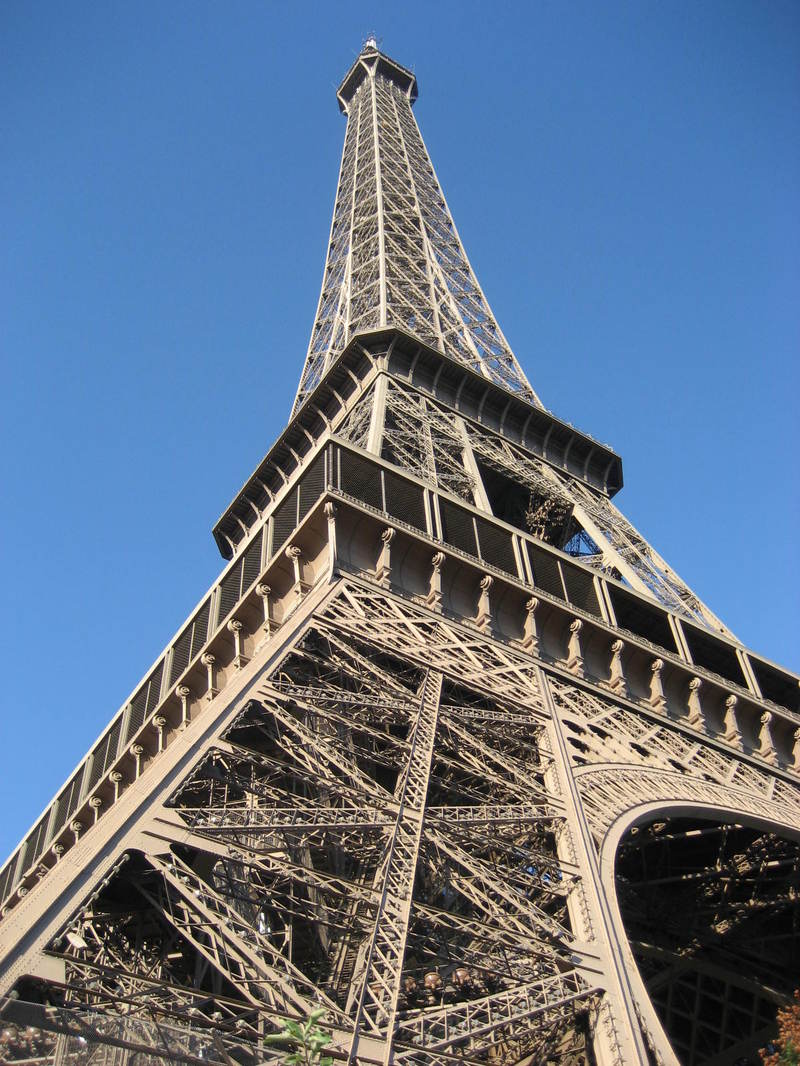 Looking up at the eiffel tower against a blue sky