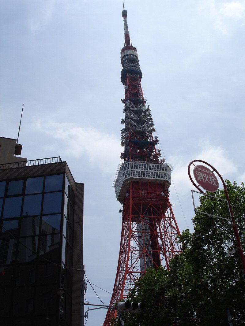 A very tall red and white tower is surrounded by trees and buildings