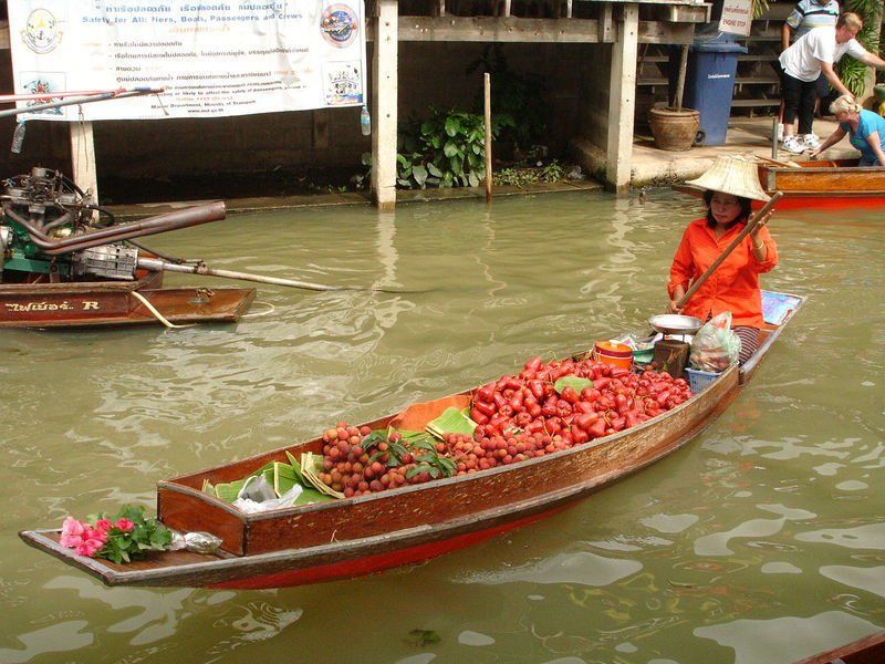 A woman is in a boat filled with fruits and flowers