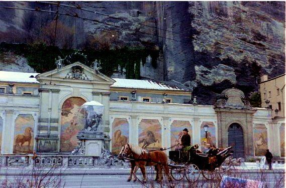 A horse drawn carriage is parked in front of a building