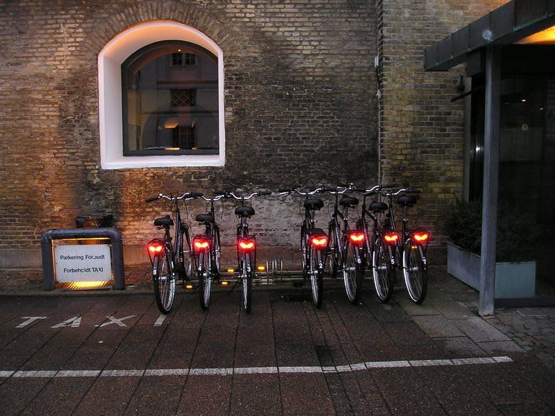 A row of bicycles are parked in front of a brick building
