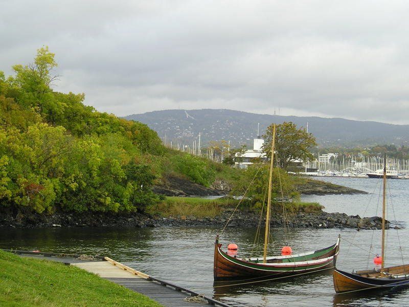 Two boats are docked in a body of water with mountains in the background