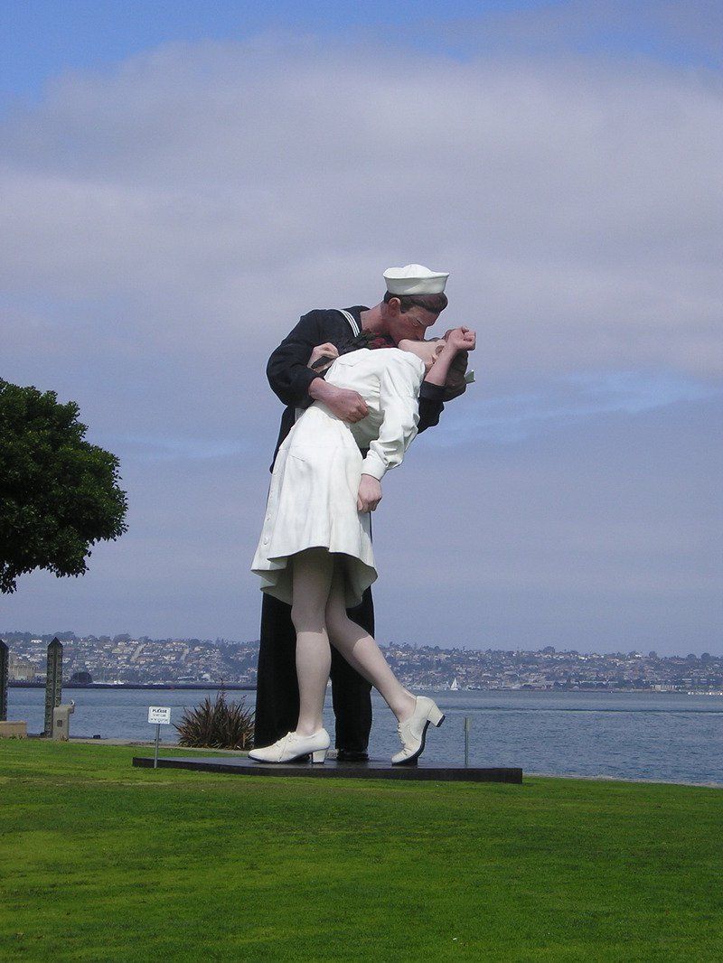 A statue of a man kissing a woman in front of a body of water