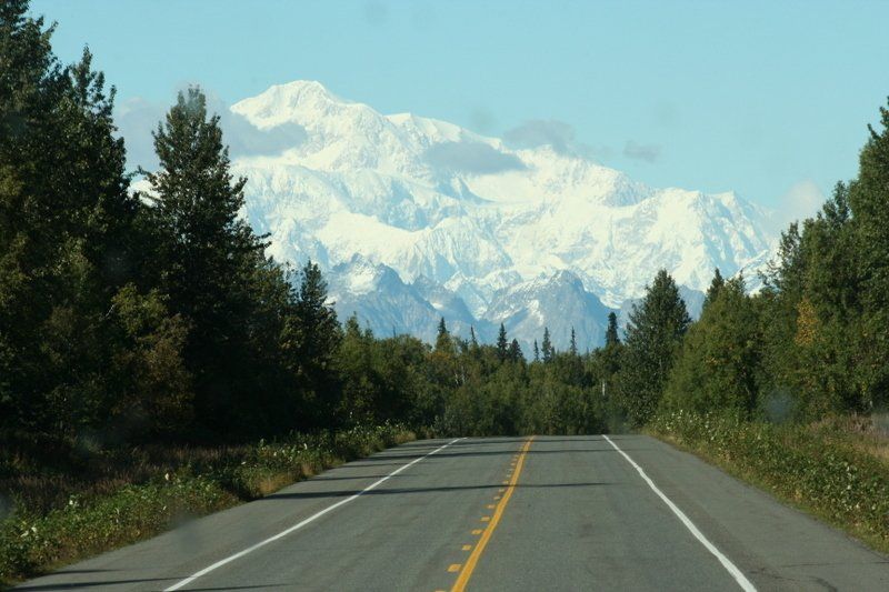 A road with mountains in the background and trees on both sides