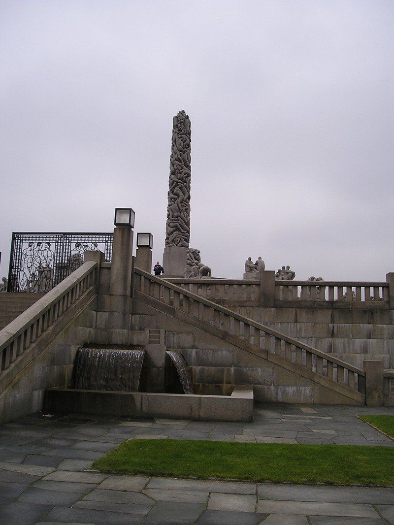 A staircase with a waterfall and a statue in the background