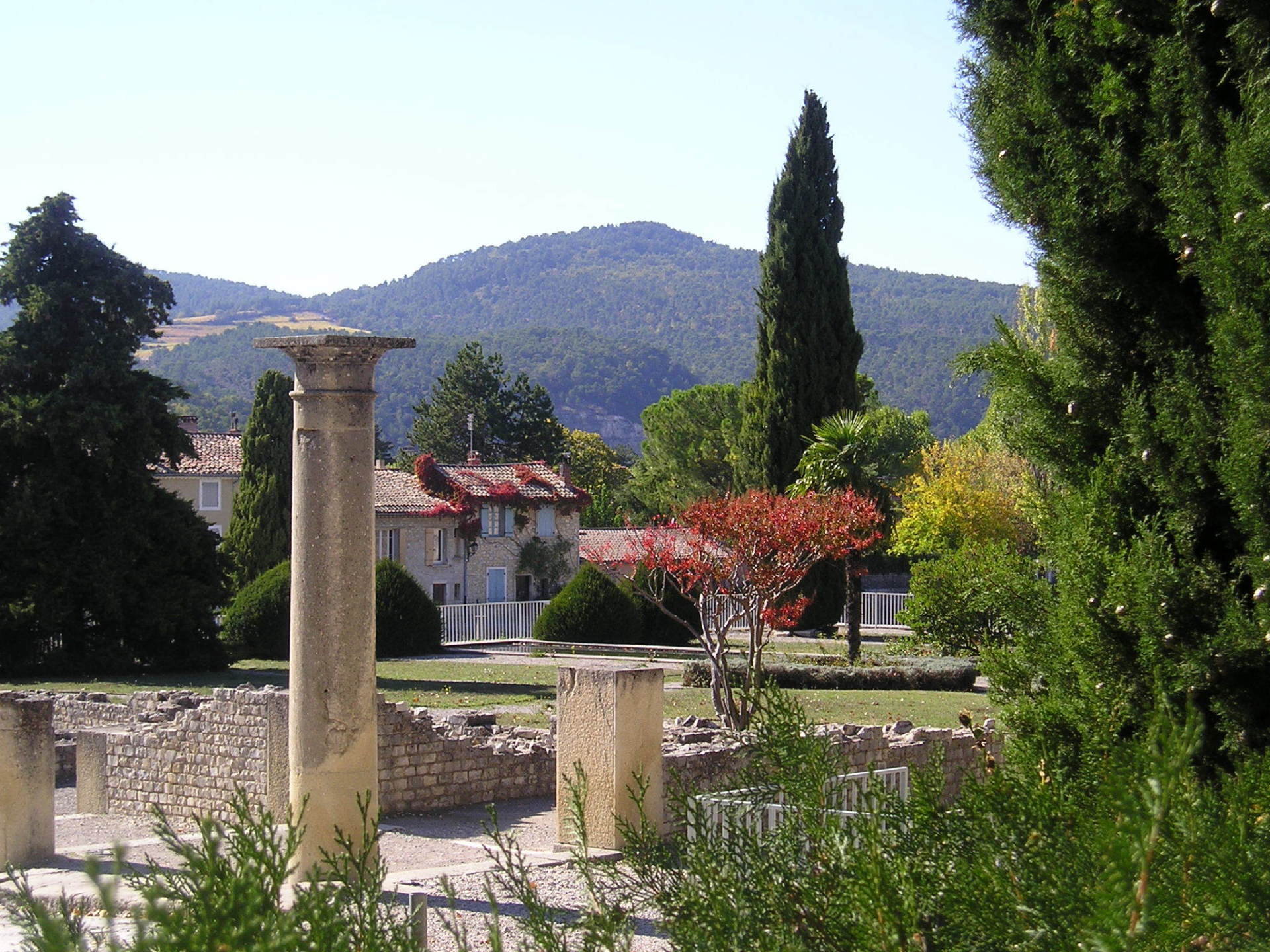 A stone column in a park with mountains in the background