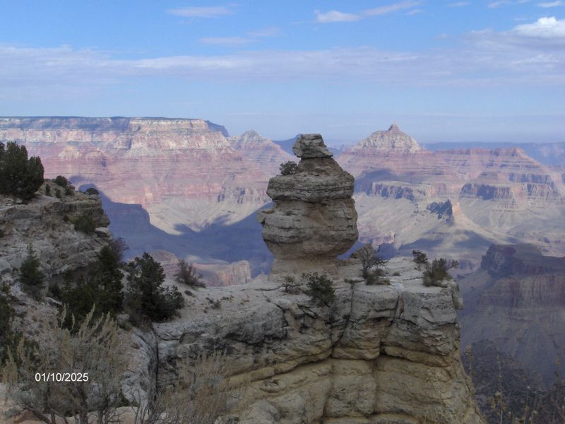 A rock formation in the middle of a canyon with mountains in the background