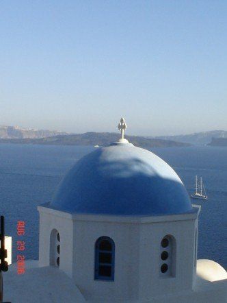 A blue dome with a cross on top of it overlooking the ocean