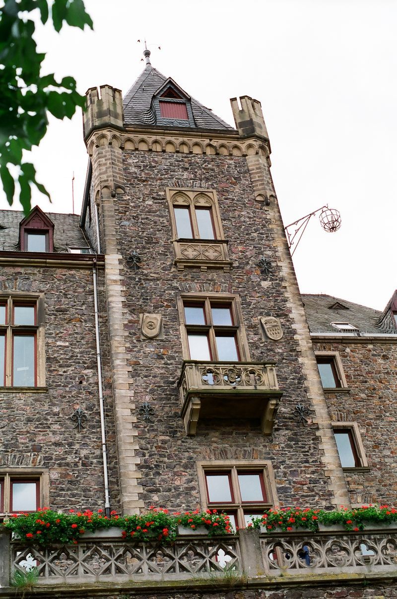 A large stone building with a balcony and flowers on it