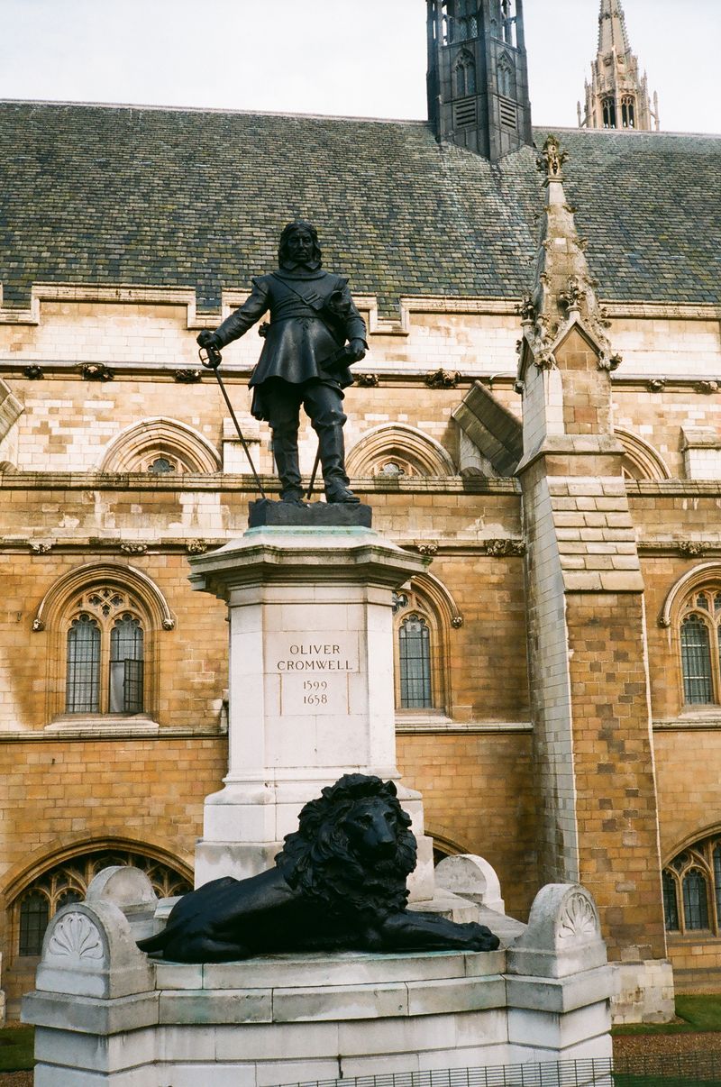A statue of a man standing next to a lion in front of a building.