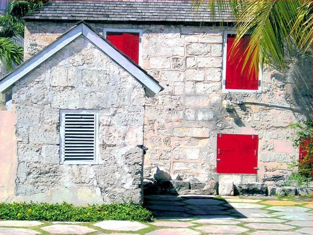 A stone house with red shutters on the windows