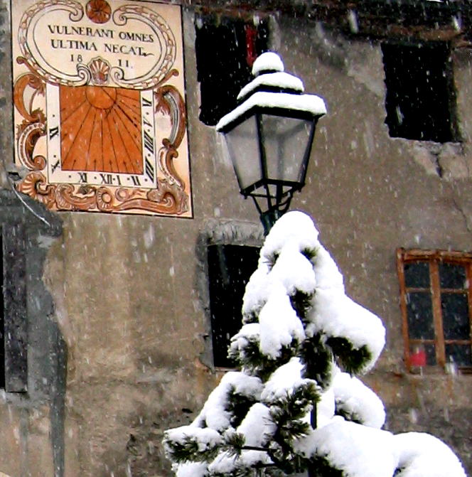 A snowy tree in front of a building with a sign above it that says ultima necal