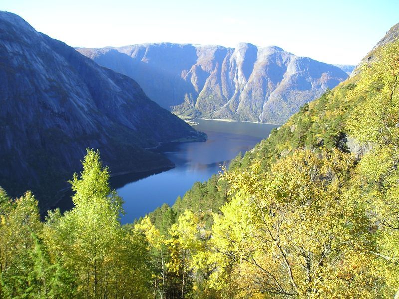 A lake surrounded by mountains and trees on a sunny day