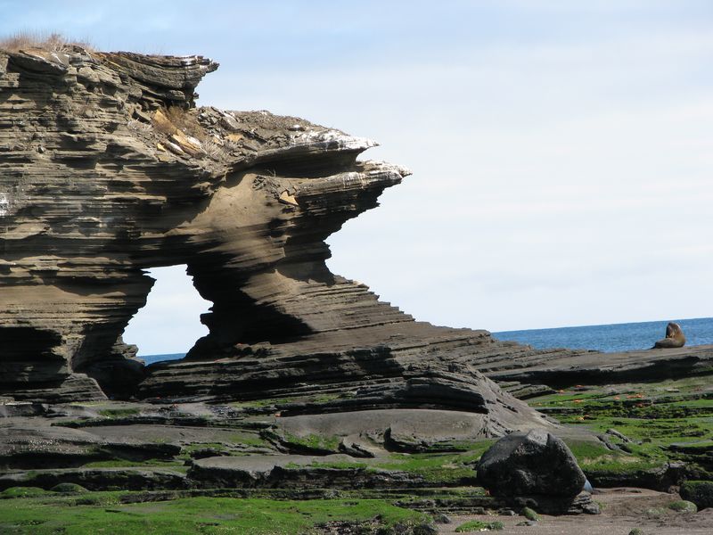A large rock formation in the middle of a grassy field