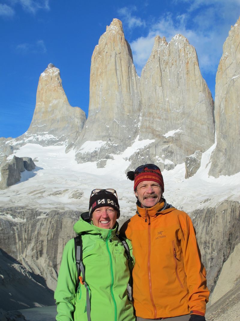 A man and a woman are posing for a picture in front of a mountain