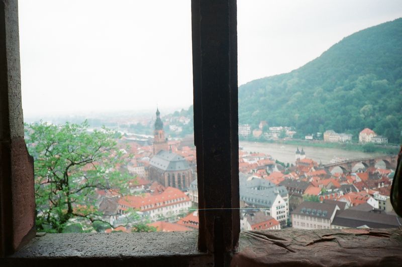 A view of a city from a window with a mountain in the background.