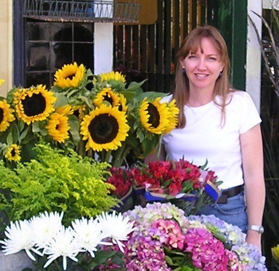 A woman is standing in front of a bunch of flowers
