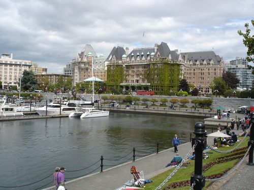 A row of boats are docked in a harbor with a large building in the background