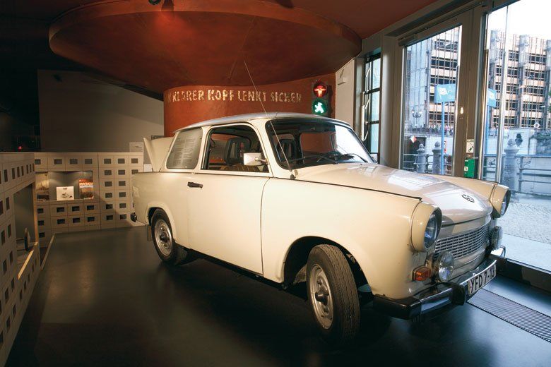 A white car is parked in a room with a red ceiling.