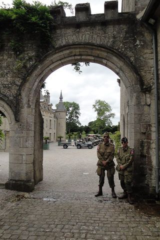 Two soldiers are standing in front of a stone archway.
