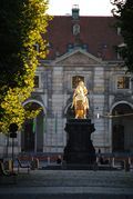 A statue of a man on a horse in front of a building.