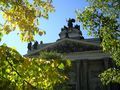 A building with a statue on top of it is surrounded by trees.