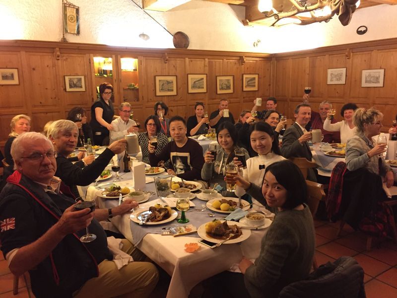 A group of people are sitting at a table in a restaurant toasting with beer mugs.