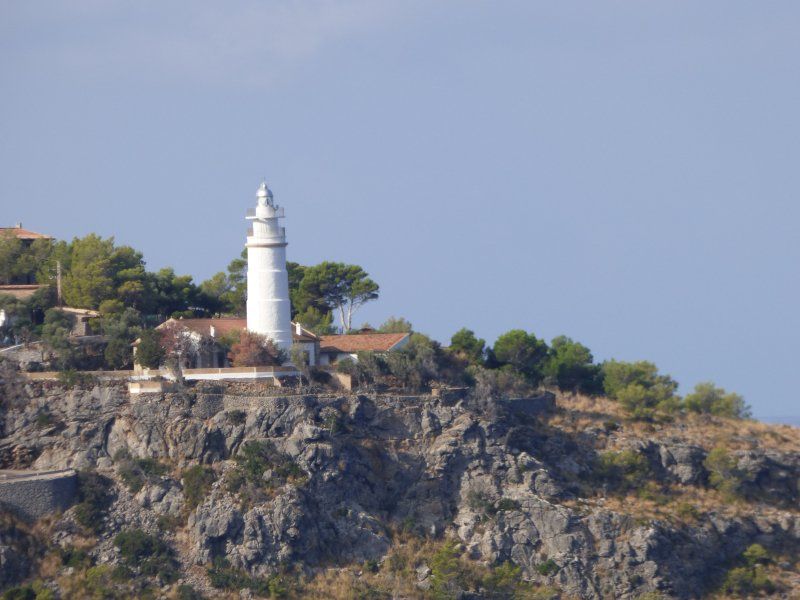 A lighthouse sits on top of a rocky hill