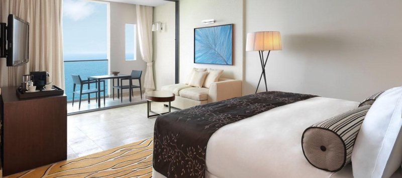 A hotel room with a large bed , couch , table and television.