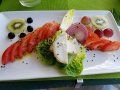 A white plate topped with a salad and fruit on a table.