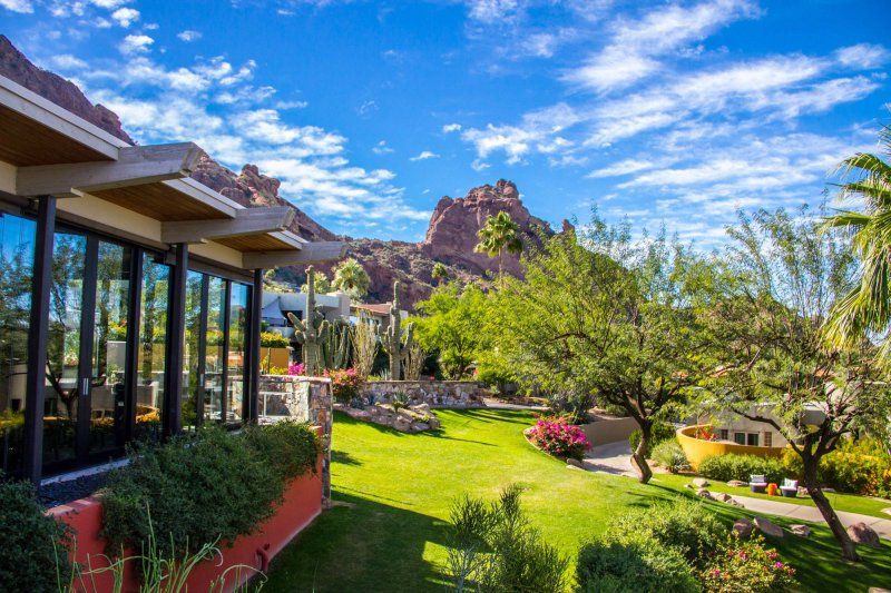 A large house with a large lawn in front of it and a mountain in the background.