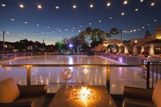 A table with a fire pit in front of an ice rink.