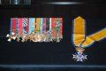 A medal and ribbons are displayed on a black background.