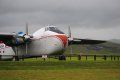 A small propeller plane is parked in a grassy field.