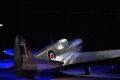 A fighter jet is sitting on the ground in the dark.