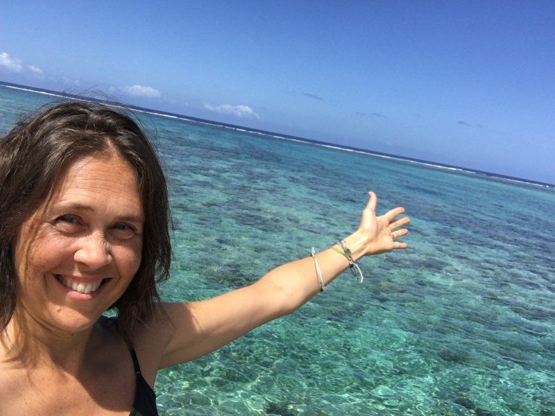 A woman is smiling and pointing at the ocean.