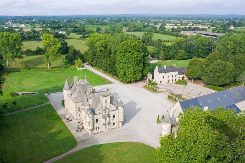 An aerial view of a large castle surrounded by trees and grass.
